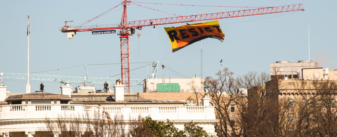 A banner reading "Resist" flying from a crane over the White House