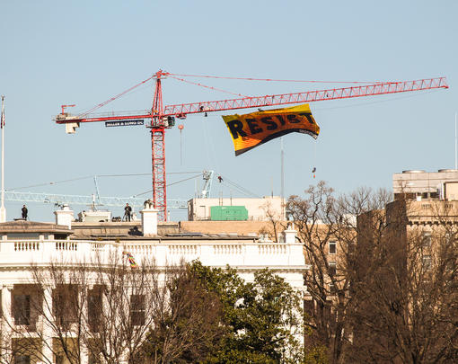 A banner reading "Resist" flying from a crane over the White House