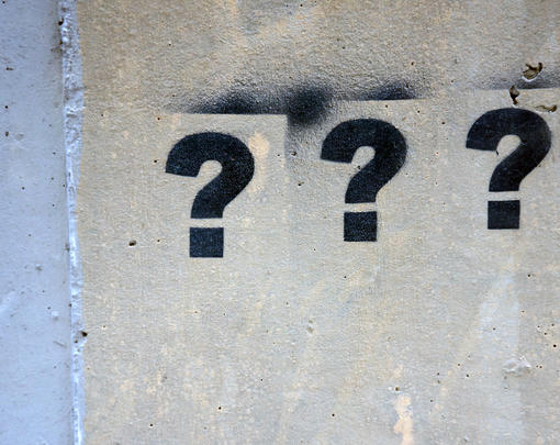 A series of question marks stenciled on a wall.