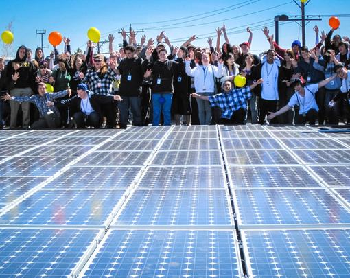 A large group of people celebrating a solar array