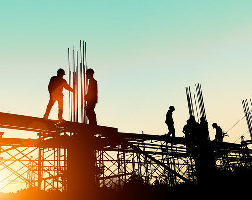Construction workers erecting a large building against the dawn