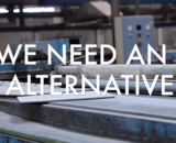 "We Need An Alternative", on top of an image of a factory.