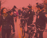 A women with a megaphone protests near a line of bicycle cops.