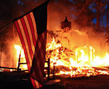 An American flag in front of a raging wildfire