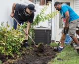 Two workers use shovels to create a rain garden