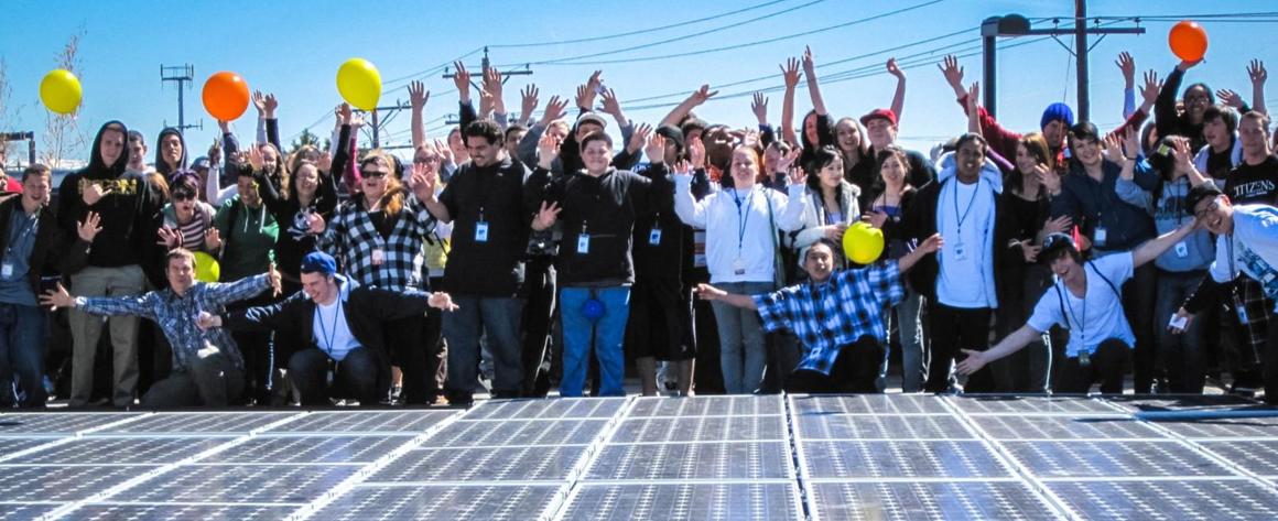 A large group of people celebrating a solar array