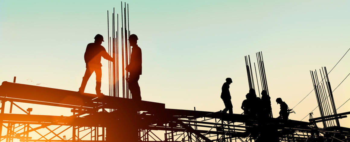 Construction workers erecting a large building against the dawn