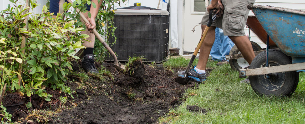 Two workers use shovels to create a rain garden